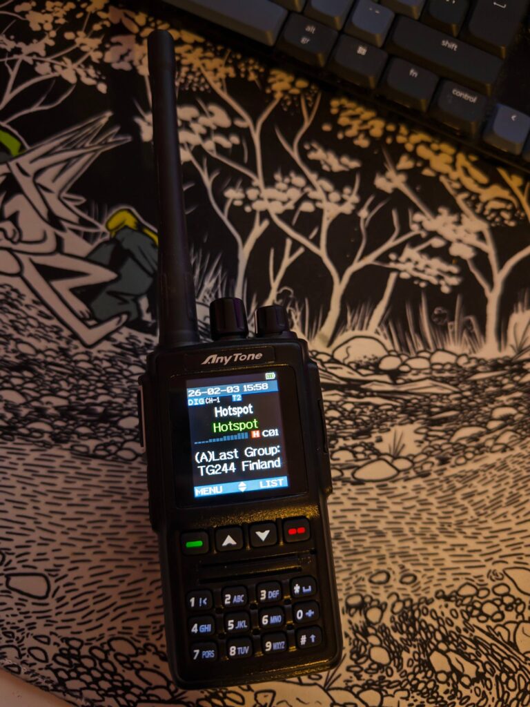 Anytone radio on a desk. Screen reads: Hotspot. Last group: Finland.